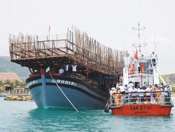 The fishing boat (L) being towed to Nha Trang Port (Photo: Thanh Nien)